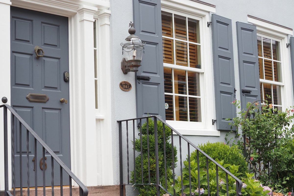 White double-hung windows with six-over-six grids and gray shutters on a pale gray house
