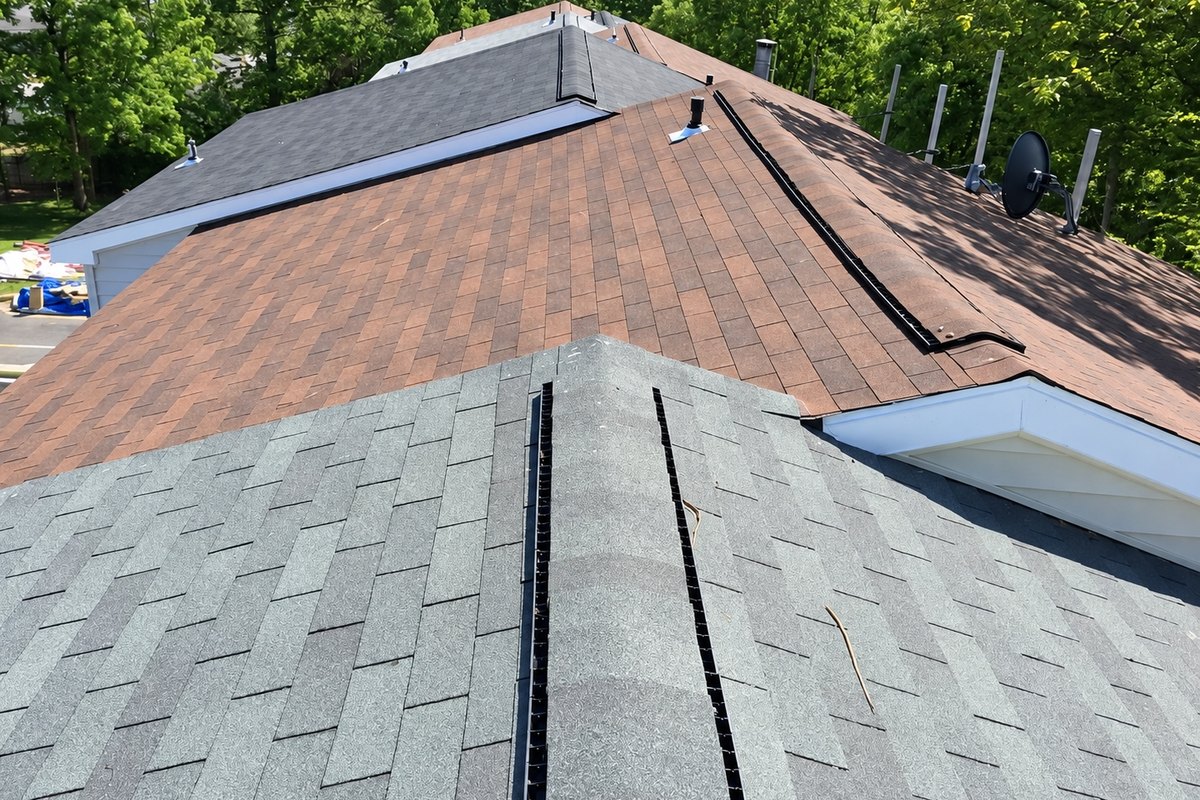 New gray ridge cap and vent strips on a townhome roof next to older shingles