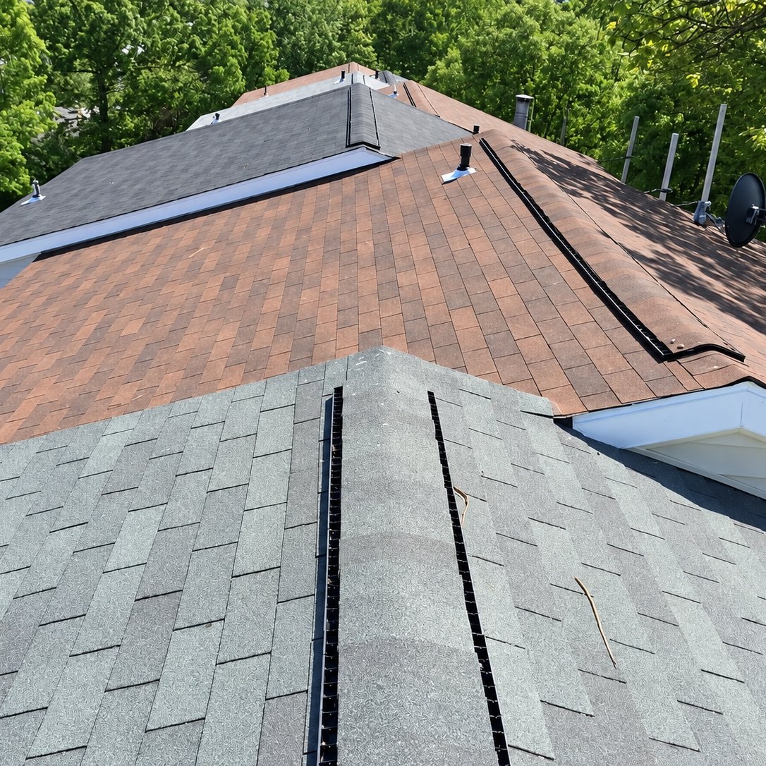 New gray ridge cap and vent strips on a townhome roof next to older shingles