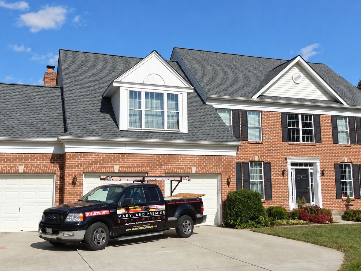 Three-car garage and dormer on a finished brick colonial with black shutters and a new gray roof