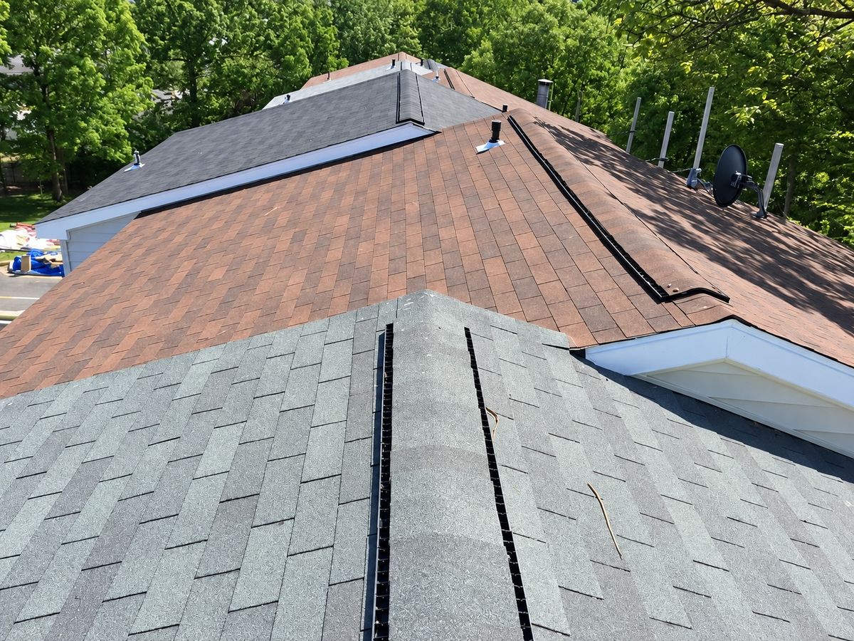 Close drone view of a townhome roof with a new gray ridge cap and vent strips on one section