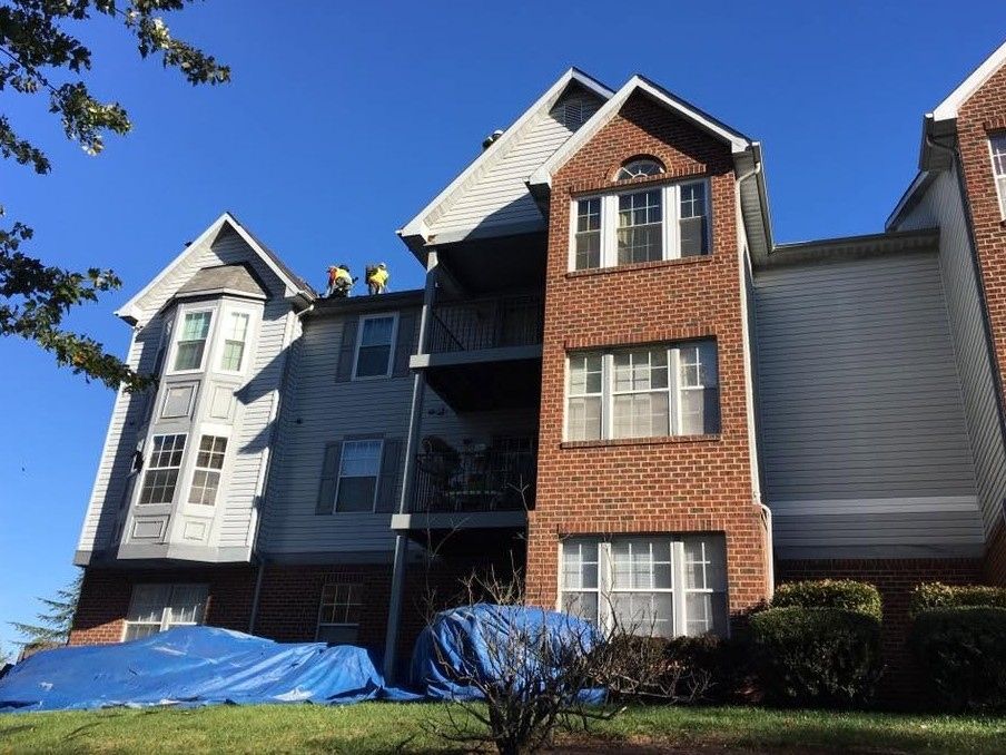 Low-angle view of a four-story apartment building with brick and gray vinyl siding