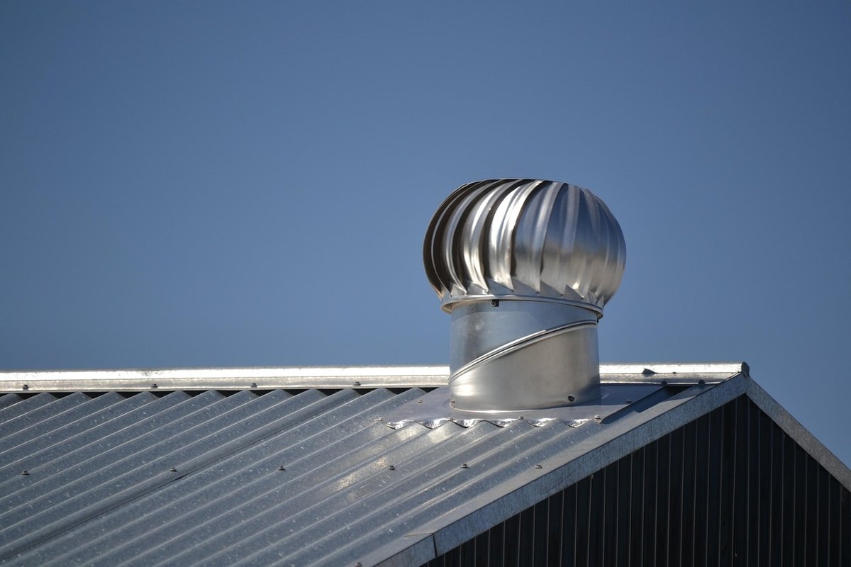 Galvanized corrugated metal roof with a turbine vent on a commercial building under a blue sky